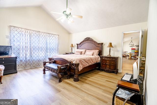 bedroom with ceiling fan, vaulted ceiling, and wood-type flooring