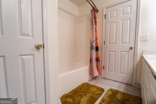 bathroom with tile patterned flooring, shower / bath combo, and vanity