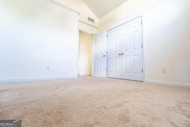 unfurnished bedroom with a closet, vaulted ceiling, and carpet flooring