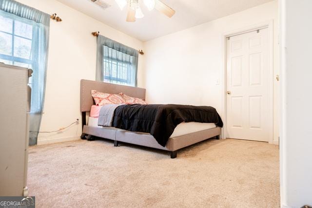 carpeted bedroom with ceiling fan and multiple windows