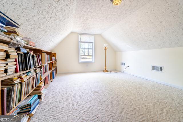 bonus room featuring a textured ceiling, vaulted ceiling, and carpet flooring