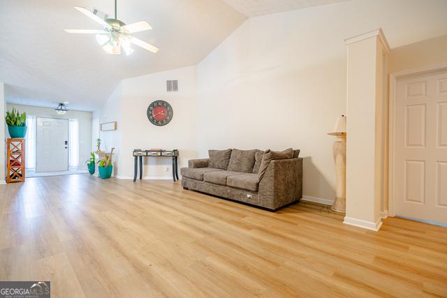 living room featuring lofted ceiling, ceiling fan, and light hardwood / wood-style flooring