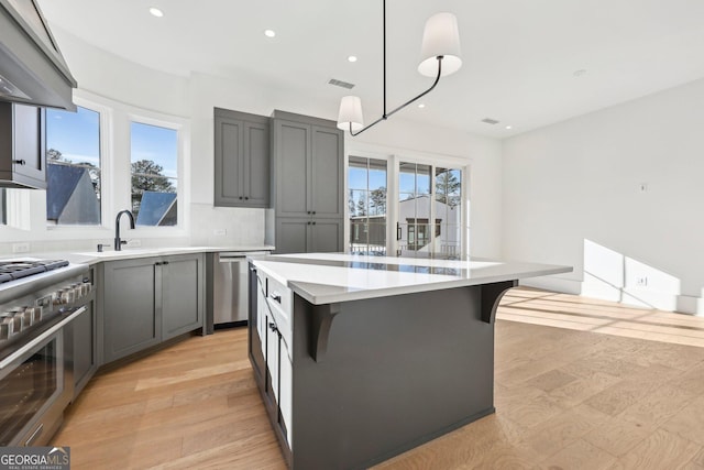 kitchen with hanging light fixtures, a breakfast bar, a kitchen island, appliances with stainless steel finishes, and sink