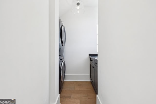 laundry room featuring stacked washer and clothes dryer and light hardwood / wood-style floors