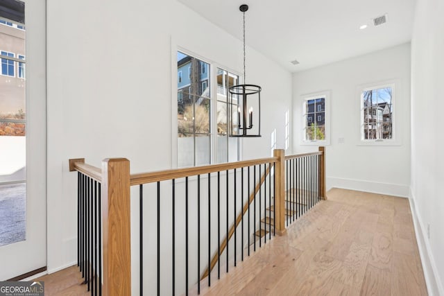 corridor with a notable chandelier and light hardwood / wood-style flooring