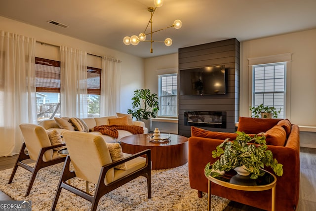 living room featuring a fireplace, wood-type flooring, and a notable chandelier