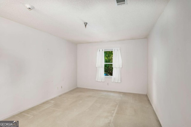 empty room featuring a textured ceiling and light colored carpet