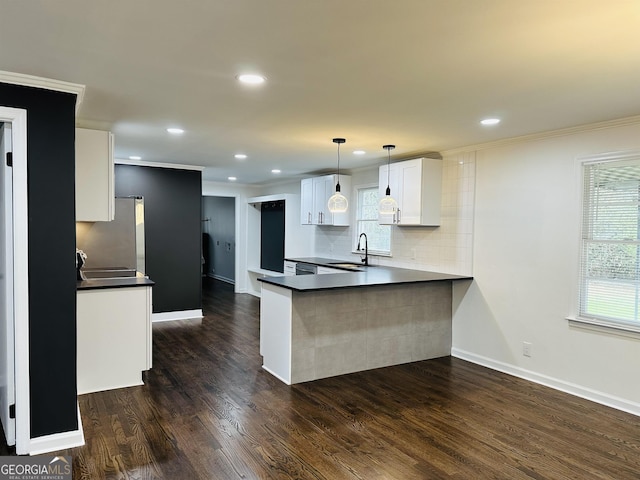 kitchen with kitchen peninsula, pendant lighting, dark hardwood / wood-style flooring, decorative backsplash, and white cabinets