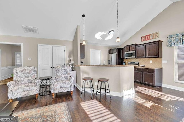 kitchen with pendant lighting, stainless steel appliances, tasteful backsplash, a kitchen breakfast bar, and dark brown cabinetry