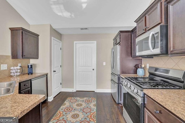 kitchen with appliances with stainless steel finishes, dark wood-type flooring, tasteful backsplash, and dark brown cabinetry