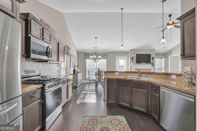 kitchen featuring decorative light fixtures, stainless steel appliances, lofted ceiling, backsplash, and sink