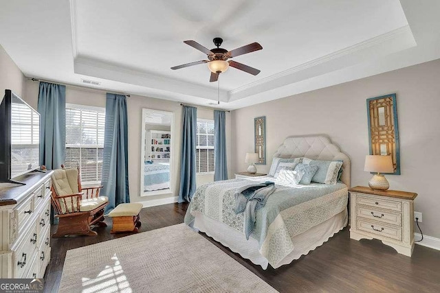 bedroom with ceiling fan, dark hardwood / wood-style flooring, crown molding, and a tray ceiling