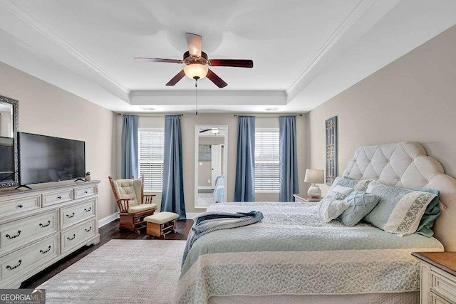 bedroom featuring a raised ceiling, ceiling fan, and multiple windows