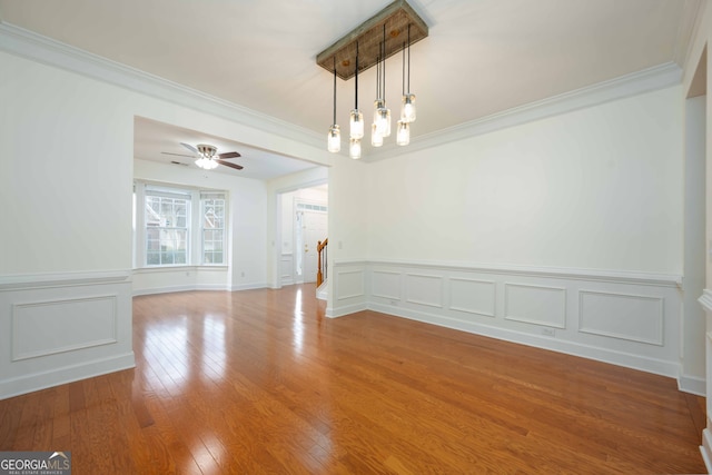 unfurnished room with ceiling fan with notable chandelier, hardwood / wood-style flooring, and crown molding