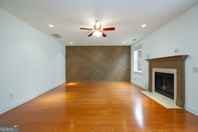 unfurnished living room with a premium fireplace, ceiling fan, and light hardwood / wood-style floors