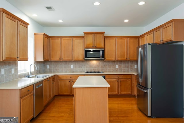 kitchen with stainless steel appliances, a center island, sink, and tasteful backsplash