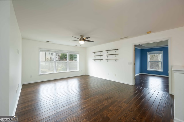 empty room featuring a healthy amount of sunlight, dark wood-type flooring, and ceiling fan