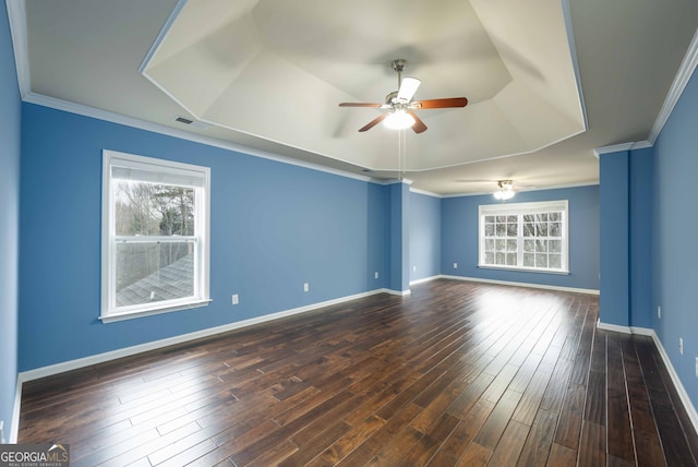 empty room featuring ceiling fan, a tray ceiling, crown molding, and dark hardwood / wood-style floors