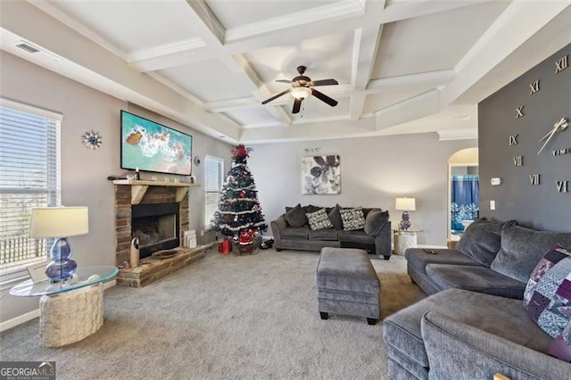 carpeted living room with a healthy amount of sunlight, a stone fireplace, coffered ceiling, and beamed ceiling