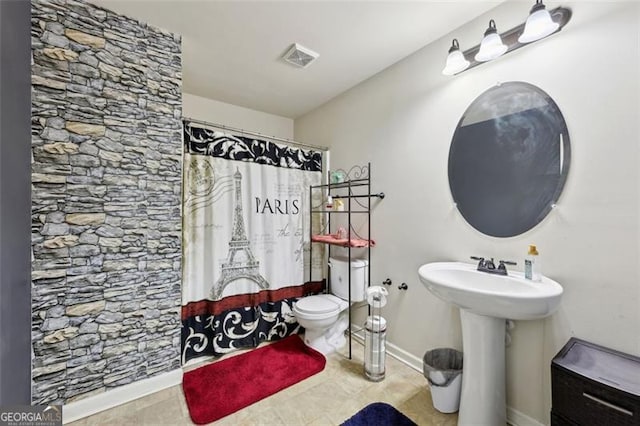 bathroom featuring toilet, sink, and a shower with curtain