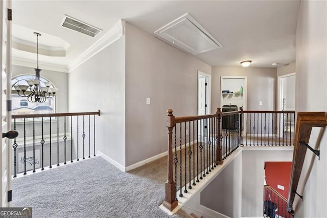 hallway with carpet flooring, an inviting chandelier, a tray ceiling, and crown molding