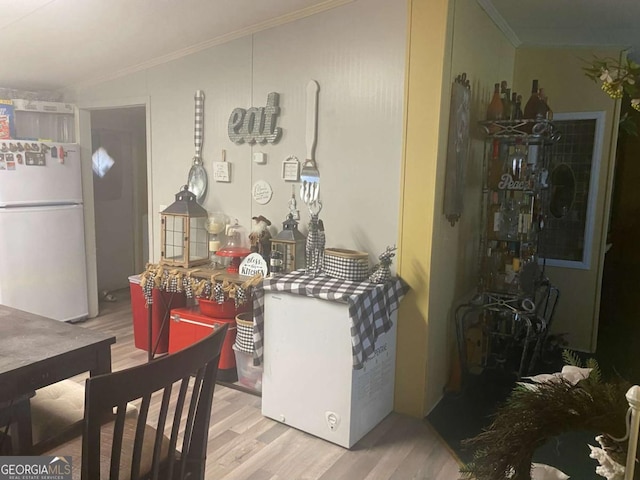 kitchen with white refrigerator, ornamental molding, and light hardwood / wood-style flooring