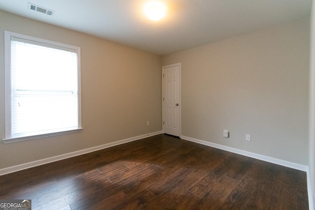 empty room featuring dark hardwood / wood-style flooring and plenty of natural light