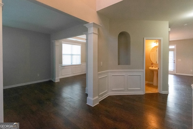 unfurnished room featuring ornate columns and dark hardwood / wood-style flooring