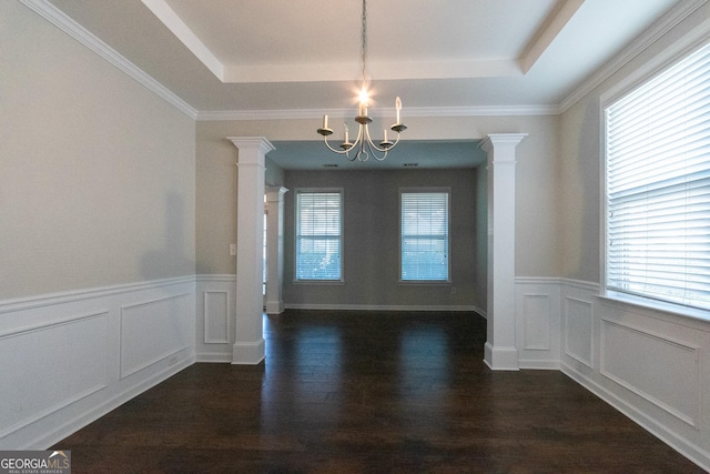 unfurnished dining area with dark wood-type flooring, a raised ceiling, a chandelier, and ornate columns