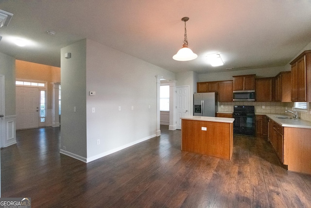 kitchen featuring stainless steel appliances, decorative light fixtures, a center island, backsplash, and dark hardwood / wood-style floors