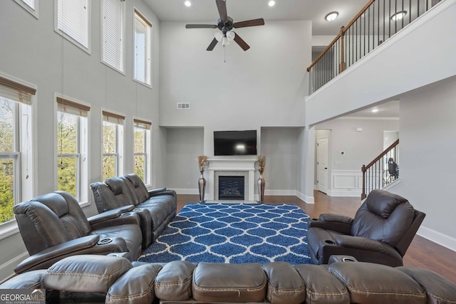 living room featuring ceiling fan, a towering ceiling, and wood-type flooring