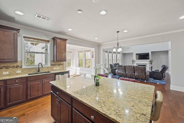 kitchen with light stone countertops, dishwasher, a center island, wood-type flooring, and sink