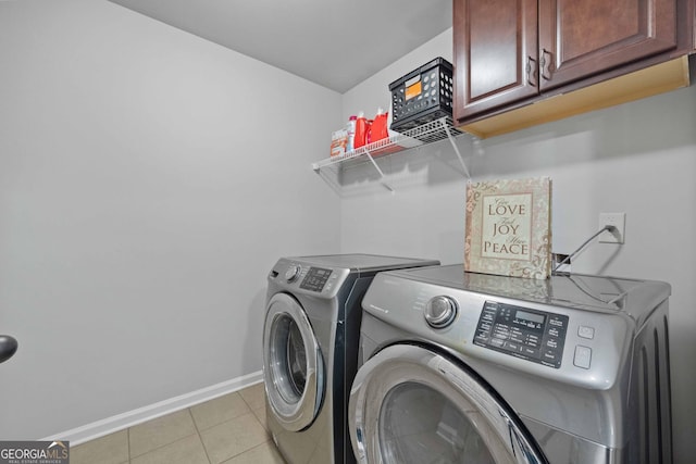 clothes washing area featuring light tile patterned floors, cabinets, and washer and dryer