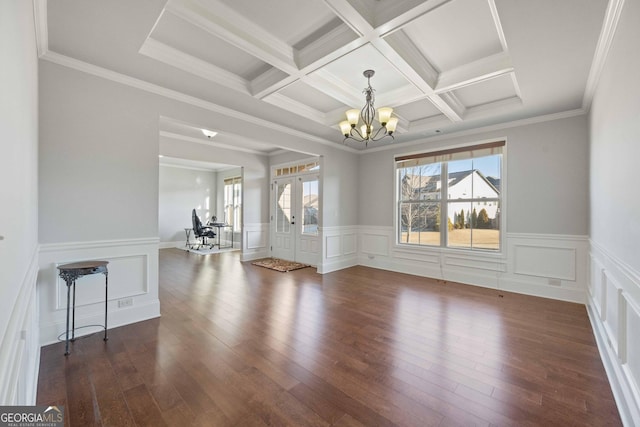 empty room with coffered ceiling, dark hardwood / wood-style floors, a chandelier, french doors, and ornamental molding