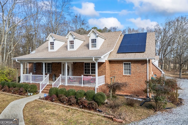 cape cod home featuring a porch and solar panels