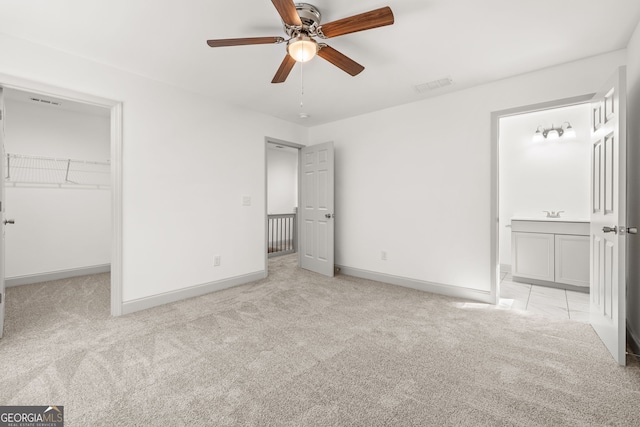 unfurnished bedroom with ceiling fan, light colored carpet, a spacious closet, and a closet