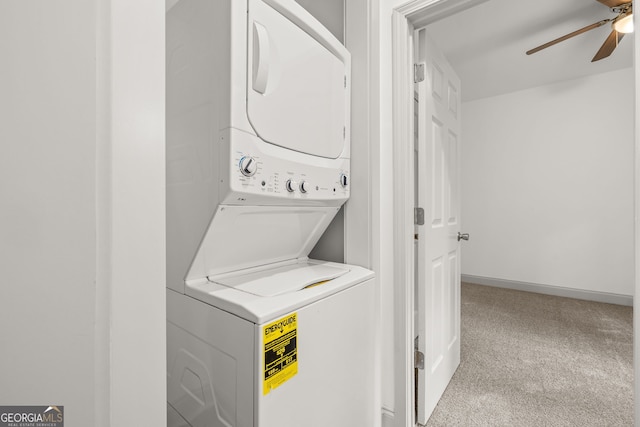 laundry area with stacked washer and clothes dryer, light colored carpet, and ceiling fan