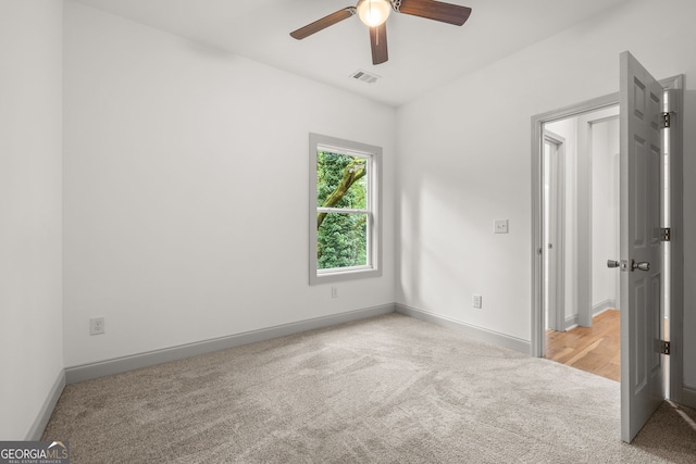 spare room featuring light colored carpet and ceiling fan