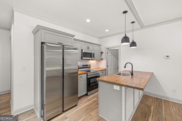 kitchen featuring sink, decorative light fixtures, butcher block countertops, gray cabinets, and appliances with stainless steel finishes