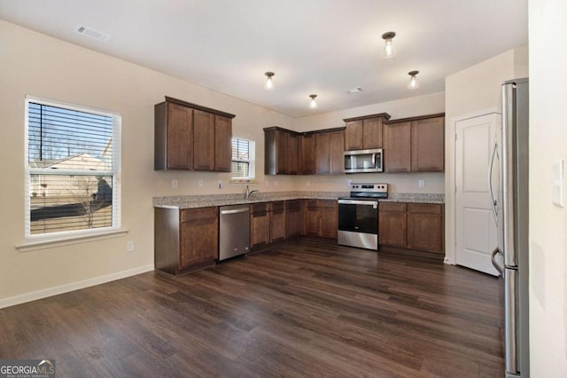 kitchen featuring dark brown cabinetry, appliances with stainless steel finishes, and dark hardwood / wood-style floors