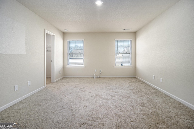 carpeted empty room with plenty of natural light and a textured ceiling