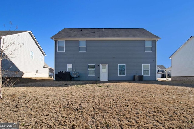 rear view of property with central AC unit and a lawn