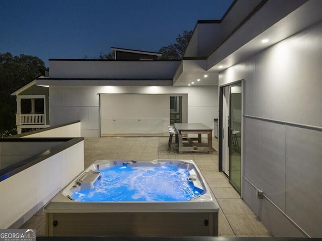 patio at night featuring an outdoor hot tub