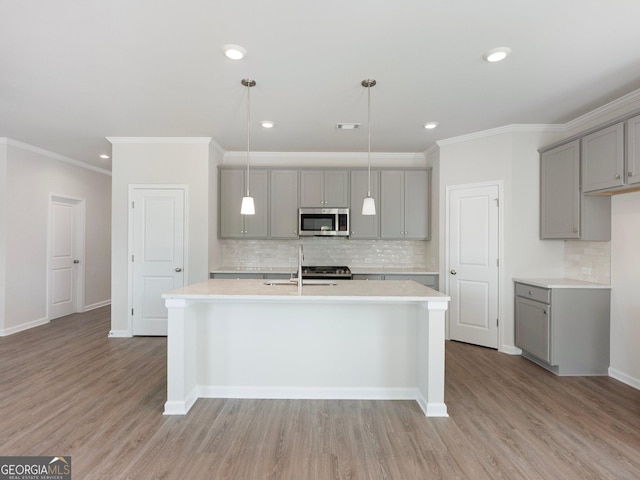 kitchen with light wood-style floors, light countertops, gray cabinets, and stainless steel microwave