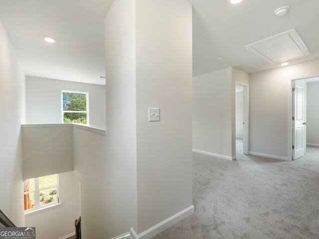 hallway with attic access, carpet flooring, a wealth of natural light, and an upstairs landing