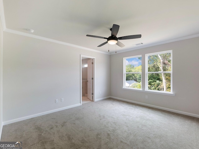 carpeted spare room featuring visible vents, crown molding, baseboards, and ceiling fan