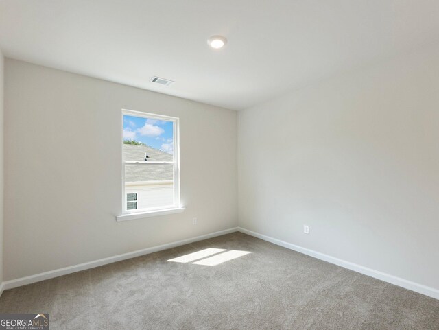 carpeted spare room with visible vents and baseboards