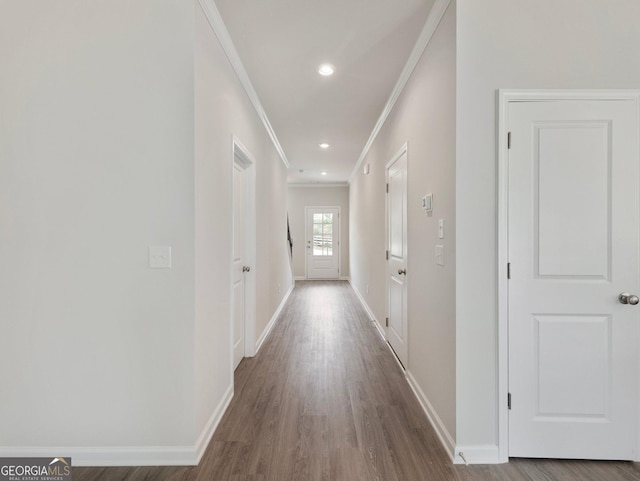 corridor featuring crown molding, baseboards, and wood finished floors