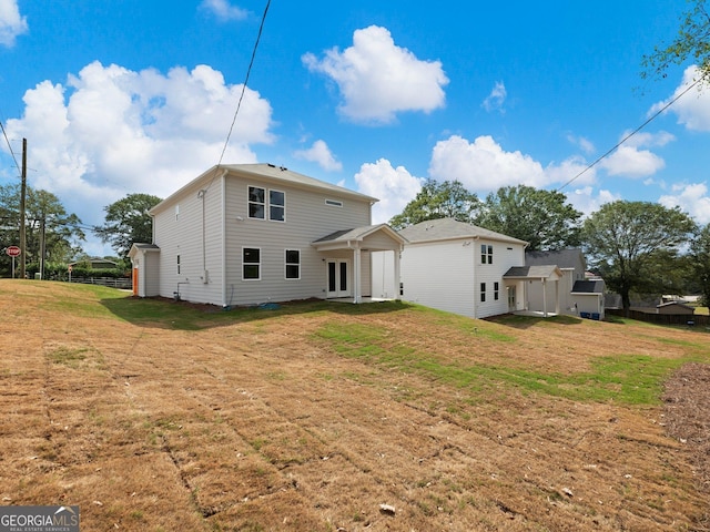 rear view of house with fence and a lawn