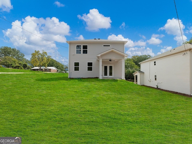 rear view of property with a ceiling fan, french doors, and a lawn